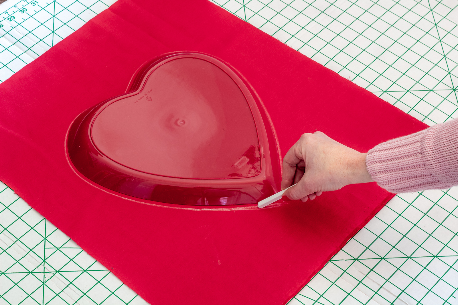 Trace or freehand a heart onto the fabric with chalk for the no sew heart pillow.