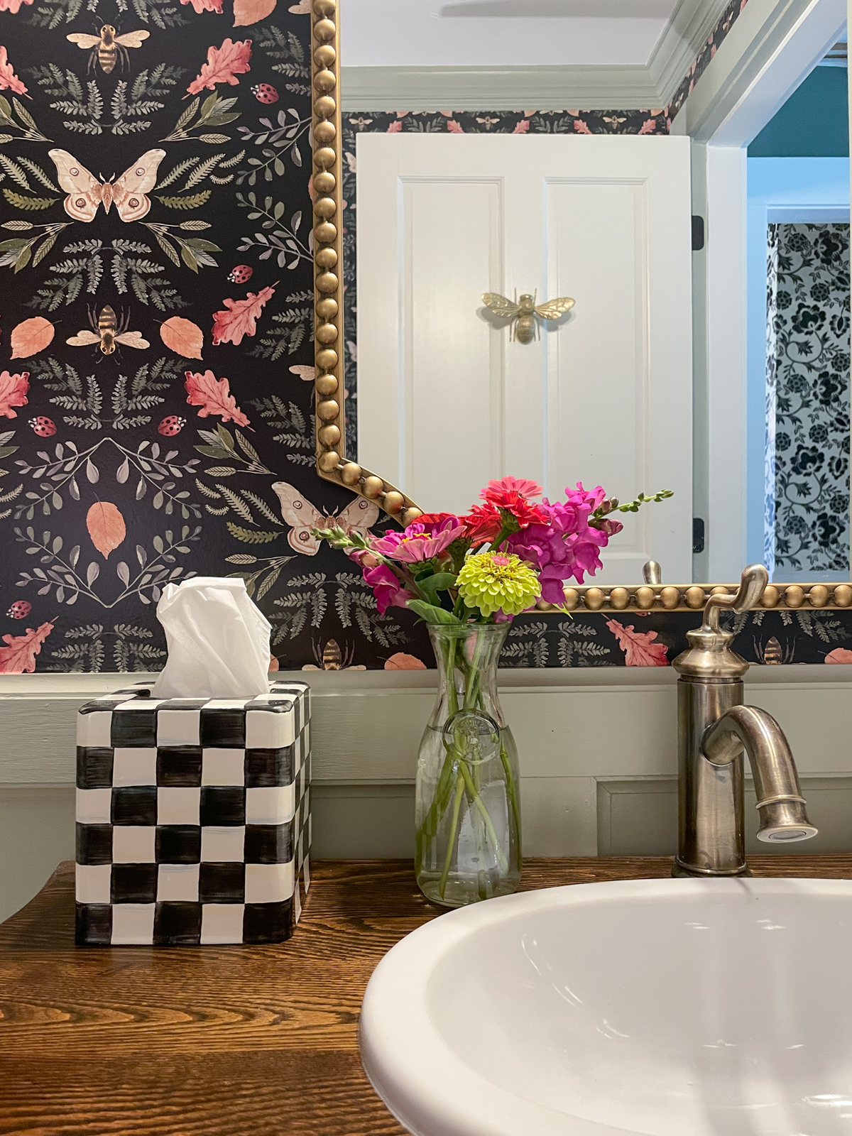 Makenzie Childs tissue holder with flowers a brass beaded mirror and botanical wallpaper
