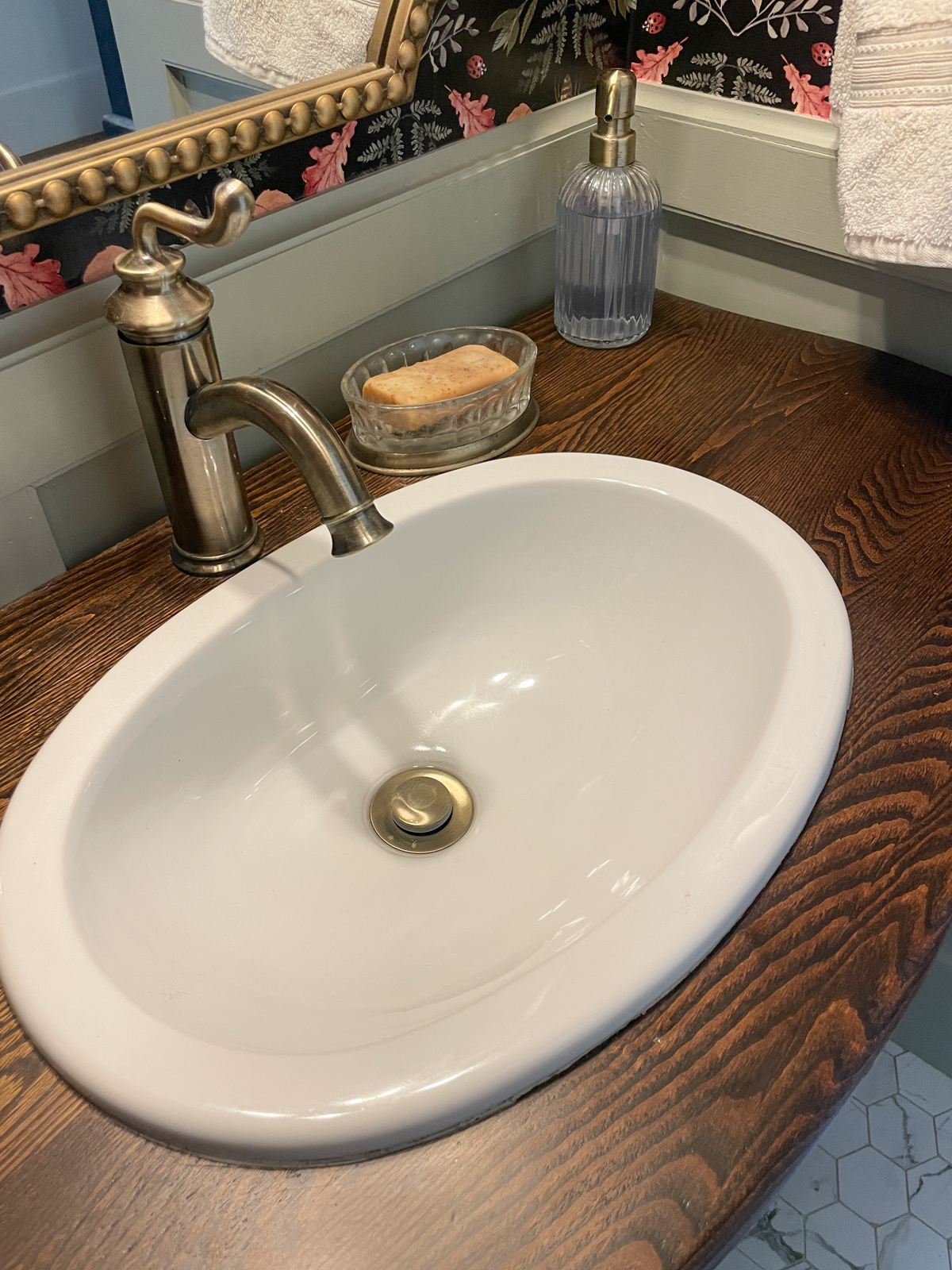 Oval sink with brass faucet installed into antique dresser vanity