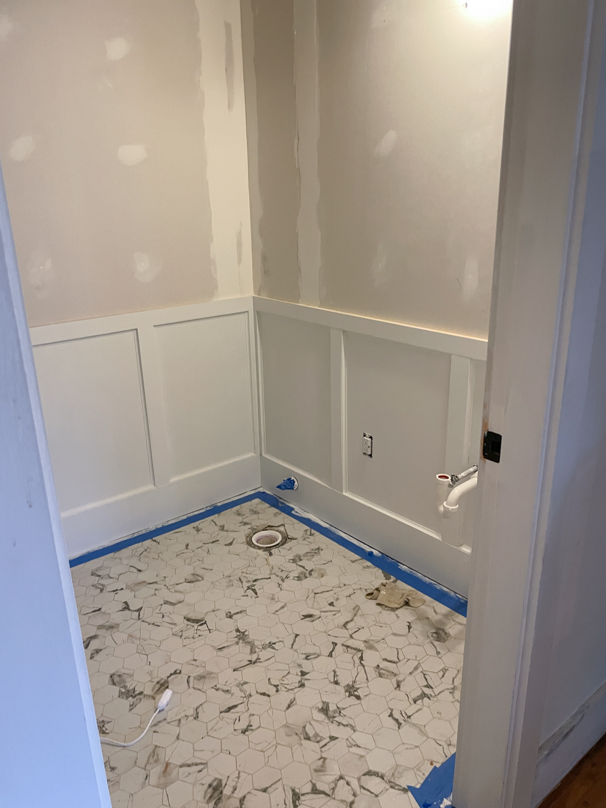 Primed wainscoting installed in the half bath before wallpaper